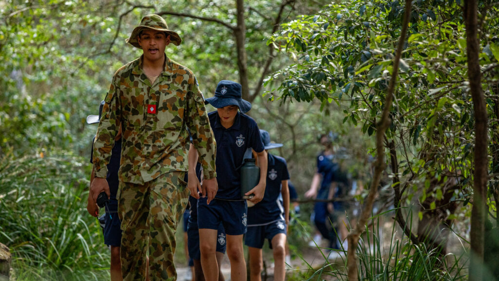 Senior King's cadet student leading younger King's boys in their sports uniforms